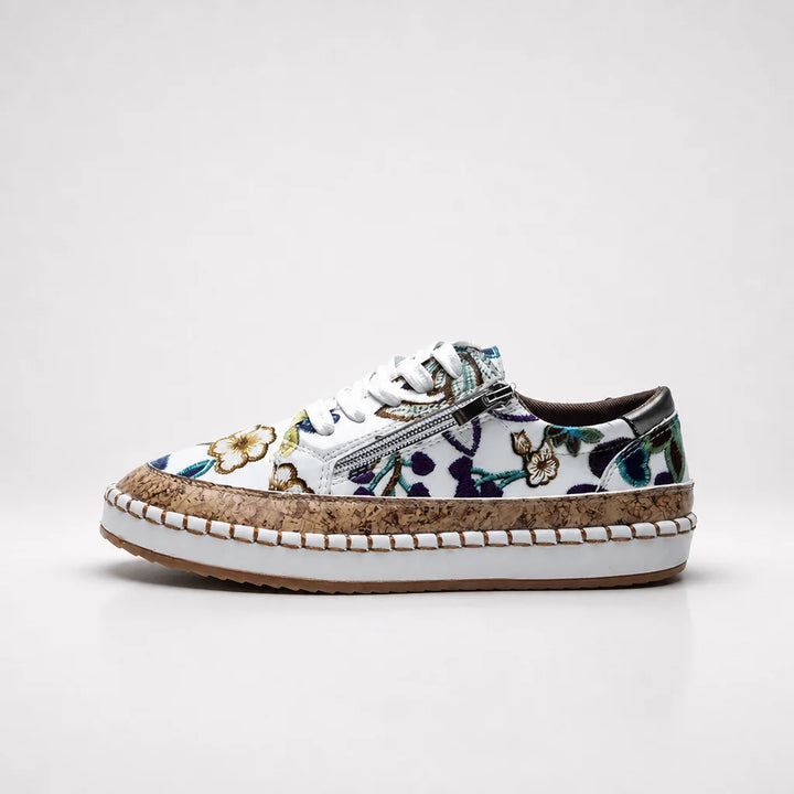 Floral low-top sneaker with cork trim and white laces on a pale studio backdrop.