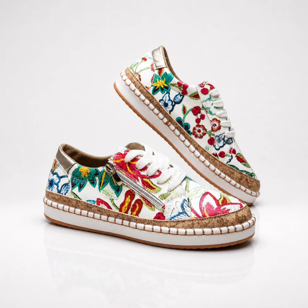Floral white sneakers with cork trim and white laces on a clean studio backdrop.