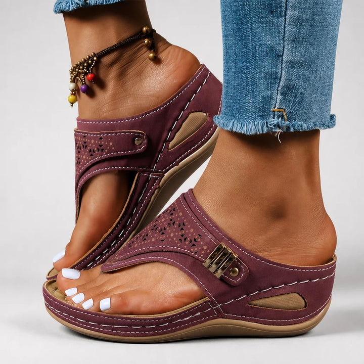 Burgundy wedge sandals worn by a model centered on a light studio background.