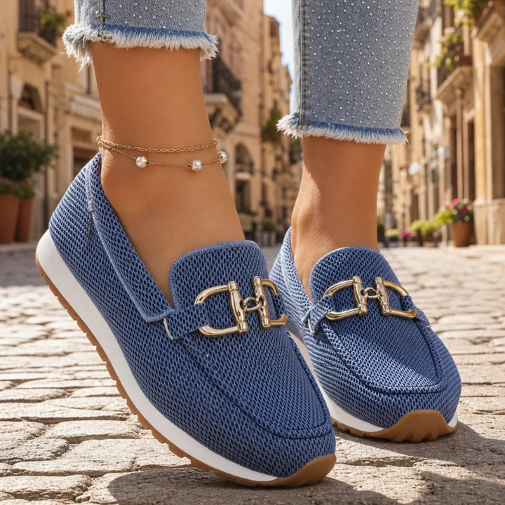 Blue mesh loafers with gold buckles worn with cropped embellished jeans on a sunny Italian street.
