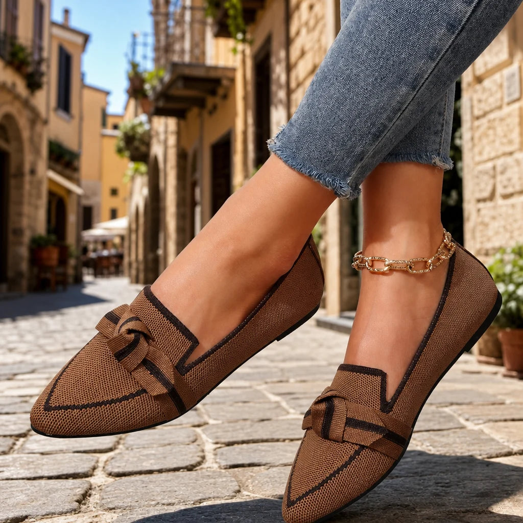 Brown woven pointed loafers with dark trim and bow detail worn with cropped jeans.